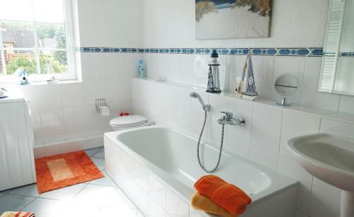 a white bathroom with a tub and a sink at Fischreiher 1 in Kappeln