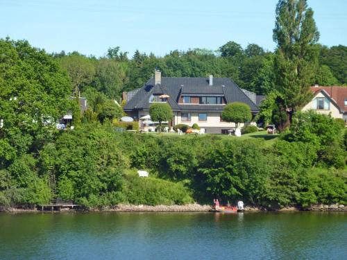 a house on a hill next to a body of water at Möwe in Kappeln