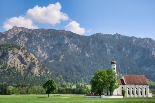 a church in a field with a mountain in the background at Ferienbungalow Schlossblick in Füssen