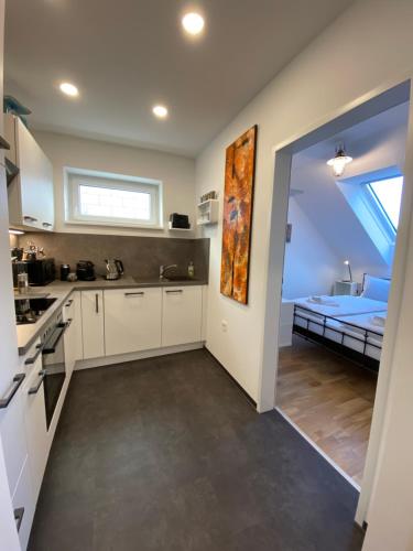 a kitchen with white cabinets and a room with a bed at ElegantLiving Graz, free parking in Graz