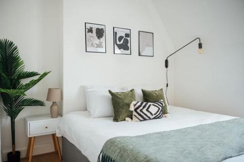 a white bedroom with a bed and a plant at Stylish Central Kings Cross 2 Bedroom Flat in London