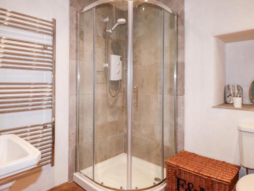 La salle de bains est pourvue d'une douche avec une porte en verre. dans l'établissement Bull Bach Old Smithy, à Pwllheli