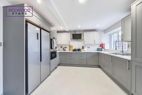 a kitchen with white cabinets and a refrigerator at HUGE 5 Bed 3 Bath House For Contractors & Families, X2 FREE PARKING, FREE WiFi & Netflix By REDWOOD STAYS in Farnborough