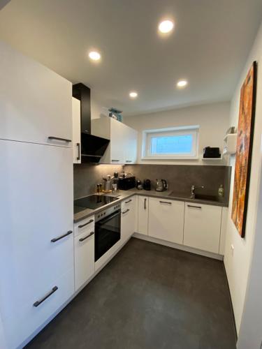 a white kitchen with white appliances and a window at ElegantLiving Graz, free parking in Graz
