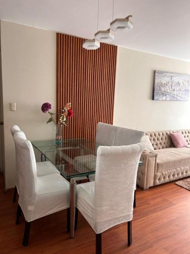 sala de estar con mesa de cristal y sillas blancas en Comodo y acogedor depa en Lince, en Lima