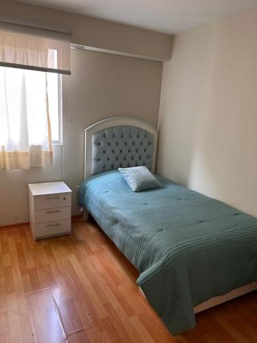 1 dormitorio con 1 cama con colcha verde y ventana en Comodo y acogedor depa en Lince, en Lima