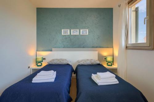 a bedroom with two beds with blue sheets and a window at Rustic villa Inga with pool and grill in Buje in Kaštel