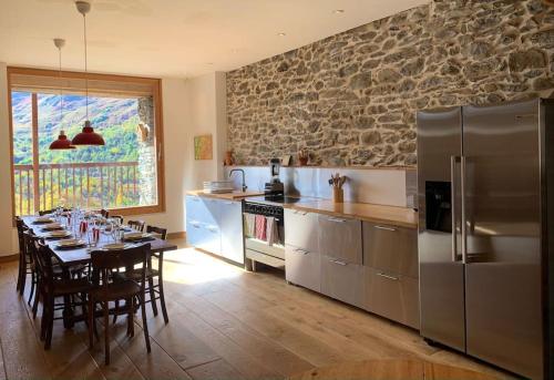 a kitchen with a table with chairs and a refrigerator at Spacieux Chalet Authentique dans les 3 Vallées in Saint-Marcel