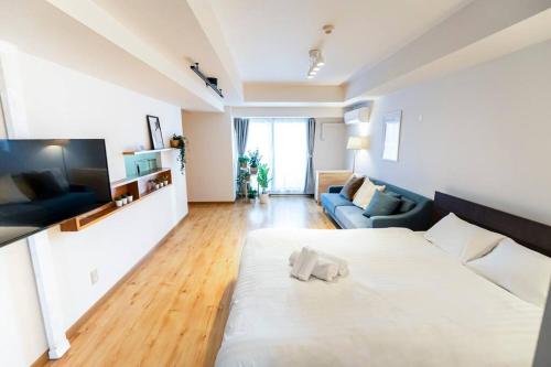 a living room with a large white bed and a couch at 今年新規OP 最大9人 すすきのエリア 札幌観光に抜群の立地 空港直通バス停すぐ 高速Wi-Fi完備 in Sapporo