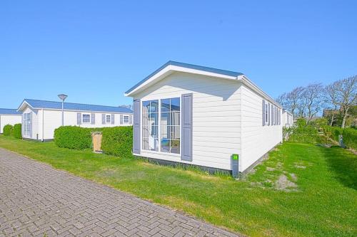 a small white house on the side of a yard at Chalet Luttikduin Nr 07 - Callantsoog aan Zee in Callantsoog