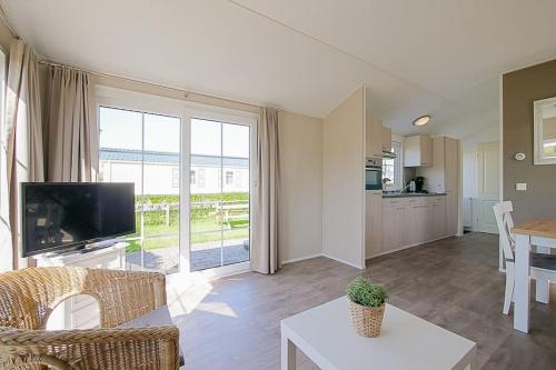a living room with a television and a table at Chalet Luttikduin Nr 07 - Callantsoog aan Zee in Callantsoog