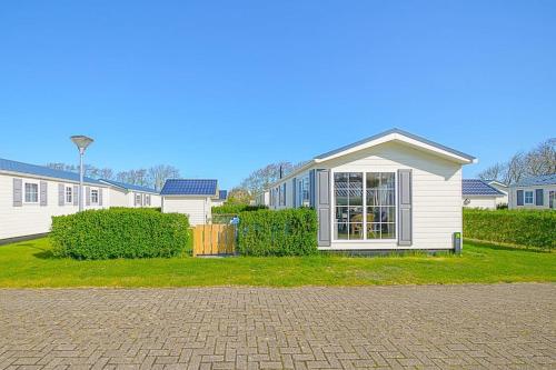 a white house with a window in a yard at Chalet Luttikduin Nr 07 - Callantsoog aan Zee in Callantsoog
