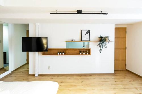 a living room with a tv on a wall at 今年新規OP 最大9人 すすきのエリア 札幌観光に抜群の立地 空港直通バス停すぐ 高速Wi-Fi完備 in Sapporo
