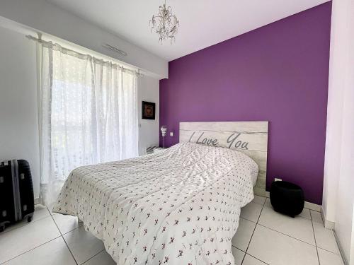 une chambre avec un lit avec un mur violet dans l'établissement Cannes - 2 pièces résidence avec parc et piscine, à Cannes