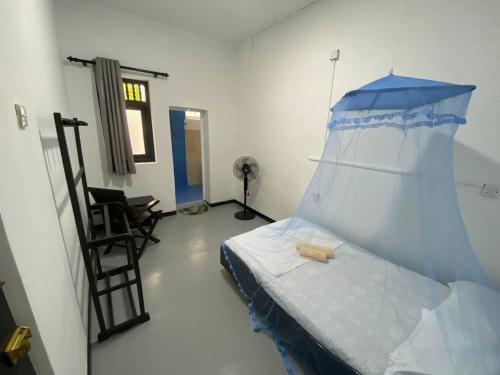 Cette chambre comprend un lit à baldaquin bleu. dans l'établissement Pearl Villa Rooms and Hostel, à Unawatuna