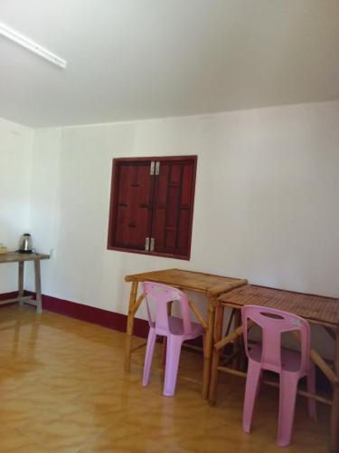 a table and two pink chairs in a room at Som PalmGarden in Ko Lanta
