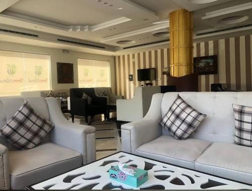أجنحة ميثاق الفندقية في الرياض: غرفة معيشة مع كنبتين وطاولة