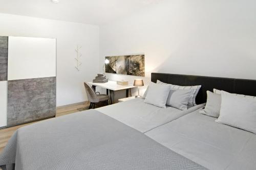 ein weißes Schlafzimmer mit einem Bett und einem Schreibtisch in der Unterkunft Lotsenbude in Wilhelmshaven