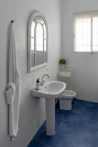 a white bathroom with a sink and a toilet at La Casa del Convento in Villamanrique de la Condesa