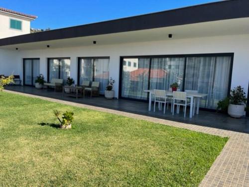 a house with a patio and a grass yard at Moradia com piscina no Caniço in Caniço