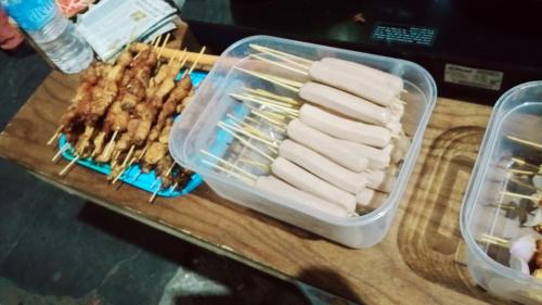 a plastic container of food on a table with skewers at Backpackers Hub in Darjeeling