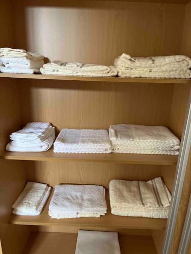 a wooden shelf with white towels and towels at Moradia com piscina no Caniço in Caniço