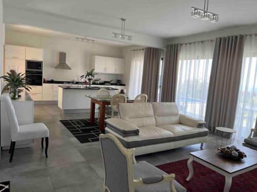 a living room with a white couch and a kitchen at Moradia com piscina no Caniço in Caniço