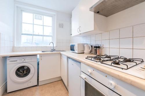 a white kitchen with a washing machine in it at Luxury 2 Bedroom Flat in Balcombe Street in London