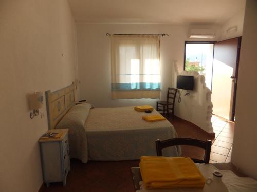 um quarto com uma cama, uma mesa e uma janela em Grazia Deledda em Galtellì
