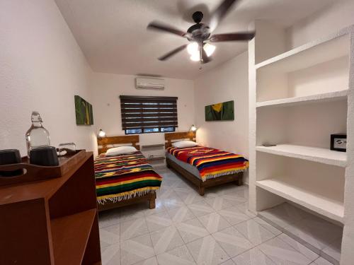 a bedroom with two beds and a ceiling fan at Casa Puerto Morelos in Puerto Morelos