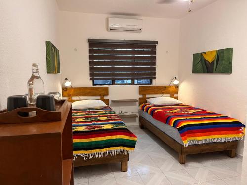 a bedroom with two beds and a desk and a sink at Casa Puerto Morelos in Puerto Morelos