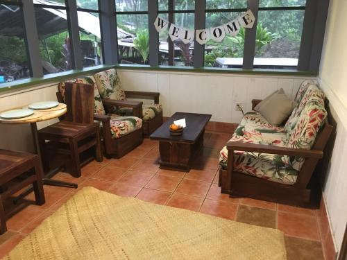 a living room with couches and a table andwindows at The Hawaii Red House Apartment Private in Keaau