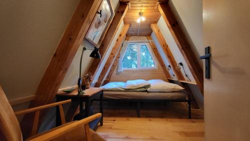 um quarto com uma cama e uma janela num sótão em Finnhütte zwischen Wald und See em Biesenthal