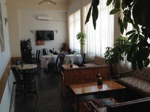 uma sala de estar com sofás, uma mesa e cadeiras em Aegli Hotel em Atenas