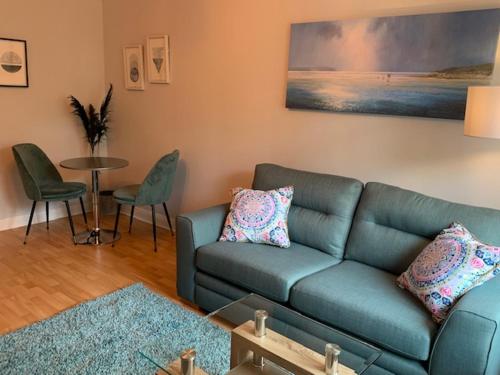 un soggiorno con divano blu e tavolo di Modern One Bedroom Apartment a Lossiemouth