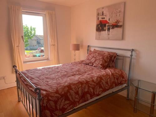 łóżko w sypialni z oknem i narzutą w obiekcie Modern One Bedroom Apartment w mieście Lossiemouth