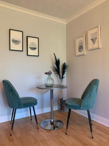 - deux chaises vertes et une table dans une pièce dans l'établissement Modern One Bedroom Apartment, à Lossiemouth