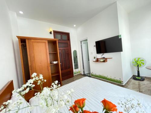 um quarto com uma cama com uma televisão e flores em Dalatdreamstay em Da Lat