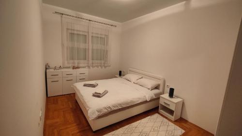 a white bedroom with a bed and a window at Apartman SUNCE in Trebinje