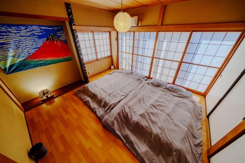 Cama grande en habitación con ventanas en LARGE HOUSE Lodging Hidamari, en Tokio