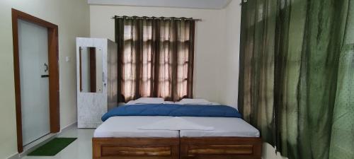 um quarto com uma cama com lençóis azuis e uma janela em Kaziranga Balaji homestay em Kaziranga