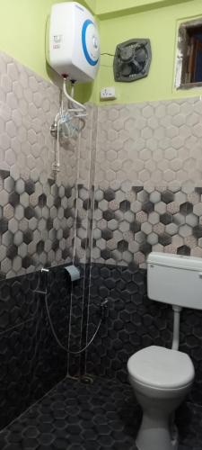 uma casa de banho com WC e secador de cabelo na parede em Kaziranga Balaji homestay em Kaziranga