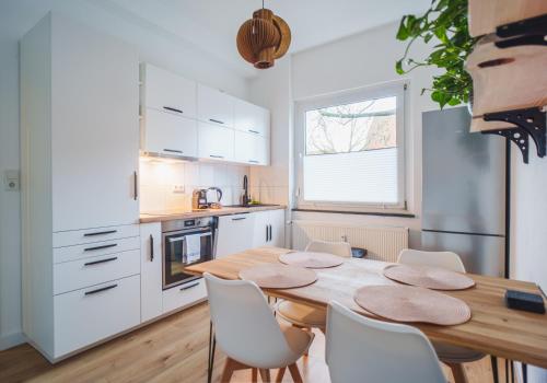 a kitchen with a wooden table and white cabinets at Apartment Innenstadt- Zentral und Exklusiv in Bestlage, Stilvolles Ambiente, alles zu Fuß erkunden in Braunschweig