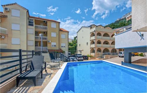 a pool with two chairs next to some buildings at 1 Bedroom Nice Apartment In Baska Voda in Baška Voda
