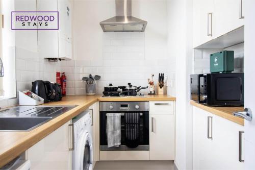 a kitchen with white cabinets and a stove top oven at Modern 1 Bed 1 Bath Apartment for Corporates & Contractors, Free Parking, Wi-Fi & Netflix By Redwood Stays in Farnborough