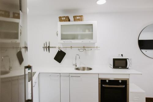 cocina blanca con fregadero y microondas en LIVING HOME COSTA BLANCA, en Calpe