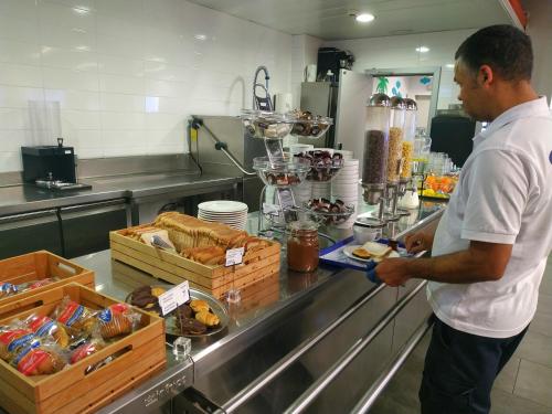 un uomo in piedi in una cucina che prepara il cibo di Twentytu Hostel Barcelona a Barcellona