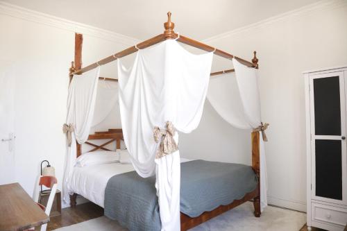 um quarto com uma cama de dossel e cortinas brancas em Appartements 4 vents by La Boîte En Plus em Senlis