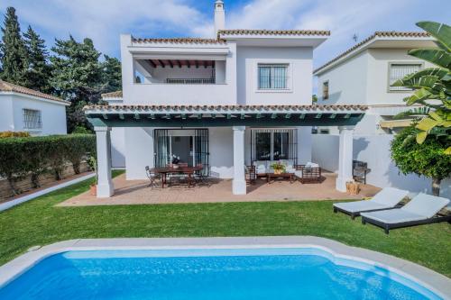 a villa with a swimming pool in front of a house at GINVA - Villa Puerto Sherry in El Puerto de Santa María