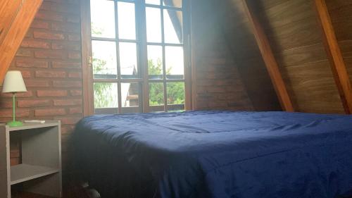 1 dormitorio con cama azul y ventana grande en Cabañas Alpinas Obligado en San Pedro